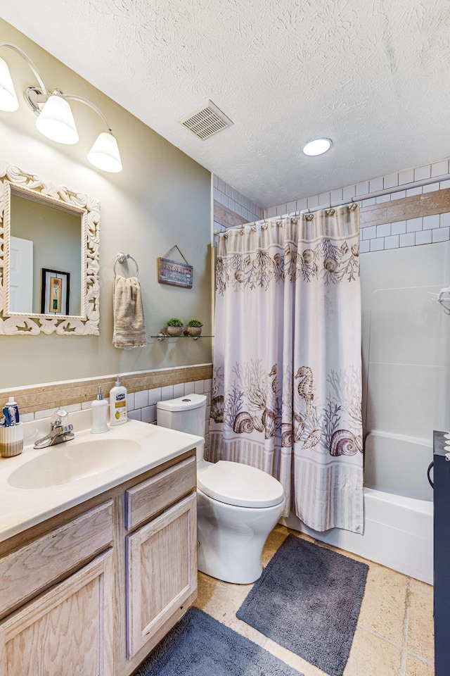 full bathroom with tile walls, vanity, a textured ceiling, and shower / bath combo with shower curtain