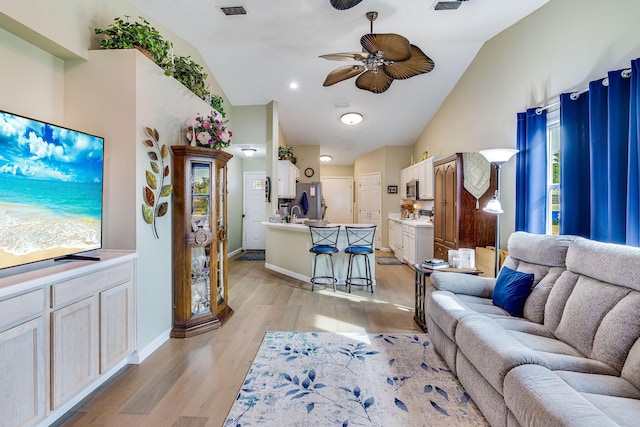 living room featuring vaulted ceiling, ceiling fan, and light wood-type flooring