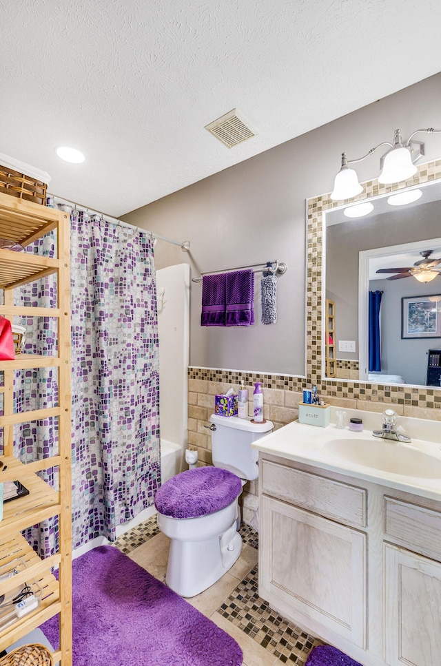 full bathroom with tile walls, tile patterned flooring, vanity, toilet, and a textured ceiling