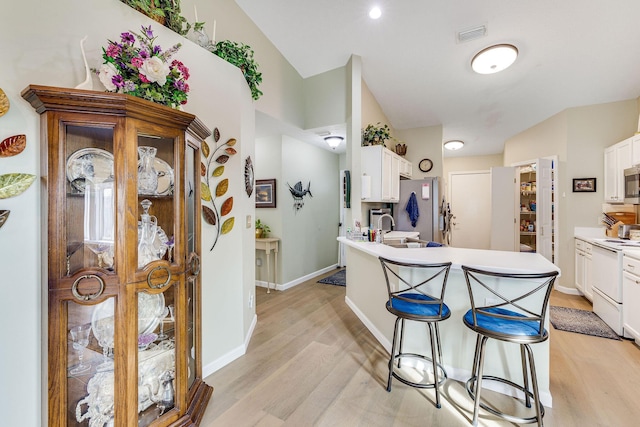 kitchen featuring appliances with stainless steel finishes, white cabinetry, sink, a breakfast bar area, and light hardwood / wood-style floors