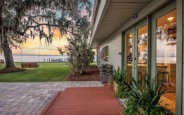 patio terrace at dusk with a yard and a water view