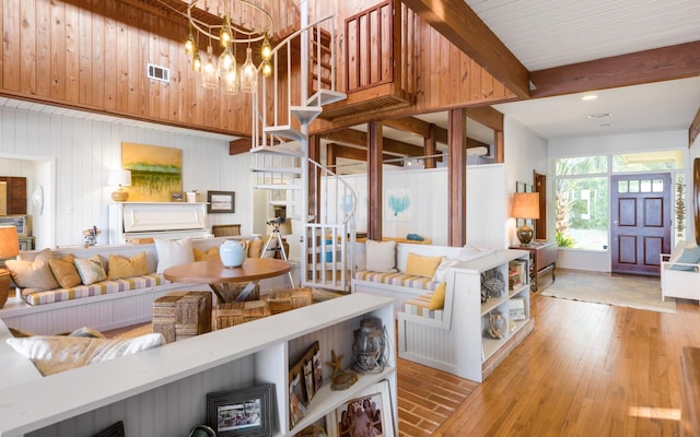 living room with beam ceiling, a chandelier, and light wood-type flooring