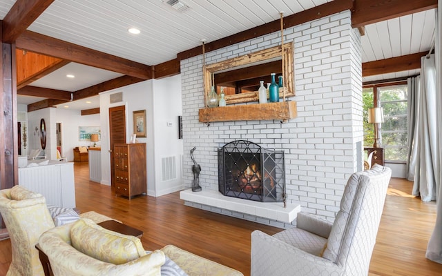 living room featuring hardwood / wood-style flooring, a fireplace, and beamed ceiling