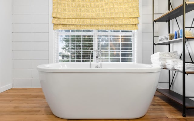 bathroom featuring wood-type flooring and a tub to relax in