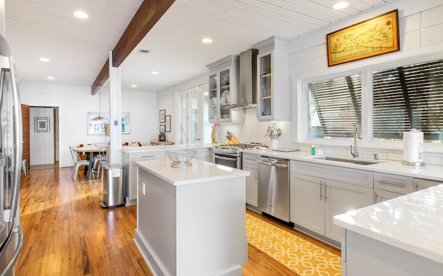 kitchen featuring appliances with stainless steel finishes, a center island, plenty of natural light, and wall chimney exhaust hood