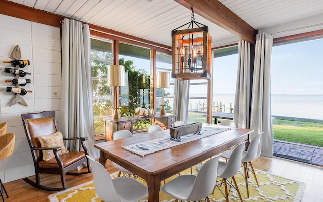 sunroom / solarium with beamed ceiling, a water view, a healthy amount of sunlight, and an inviting chandelier