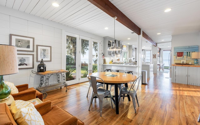 dining area featuring beamed ceiling, a healthy amount of sunlight, and light hardwood / wood-style flooring