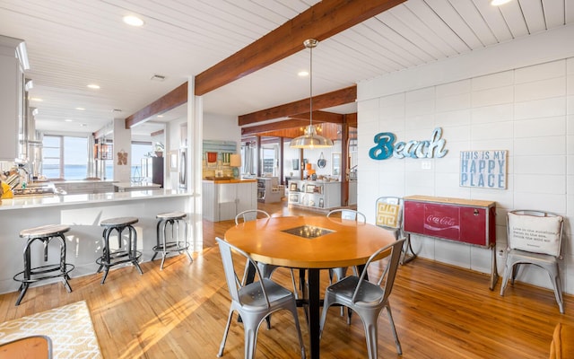 dining area with beamed ceiling and light hardwood / wood-style floors