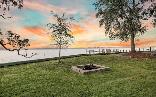 yard at dusk featuring a water view and an outdoor fire pit