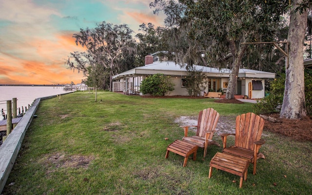 yard at dusk featuring a water view