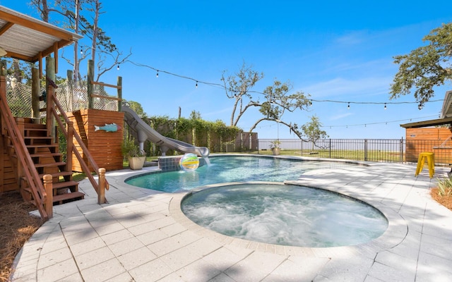 view of swimming pool with an in ground hot tub, a water slide, and a patio area