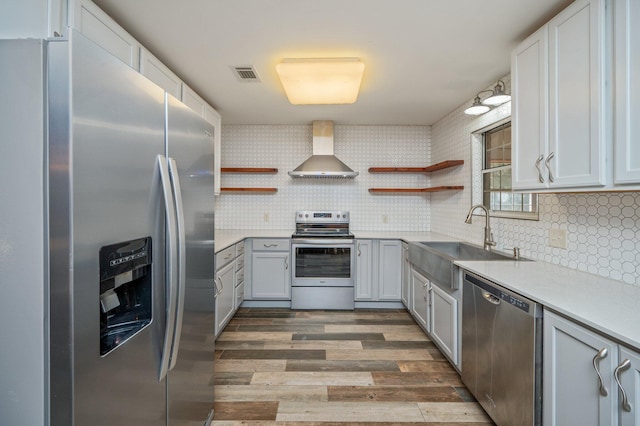 kitchen featuring wall chimney exhaust hood, sink, dark hardwood / wood-style floors, stainless steel appliances, and decorative backsplash