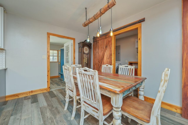 dining room featuring wood-type flooring, a barn door, and electric panel