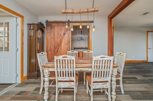 dining room with a barn door and dark wood-type flooring