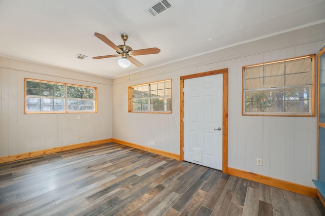 empty room featuring crown molding, dark wood-type flooring, and ceiling fan