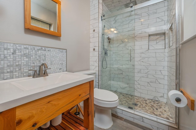 bathroom with backsplash, hardwood / wood-style flooring, vanity, walk in shower, and toilet