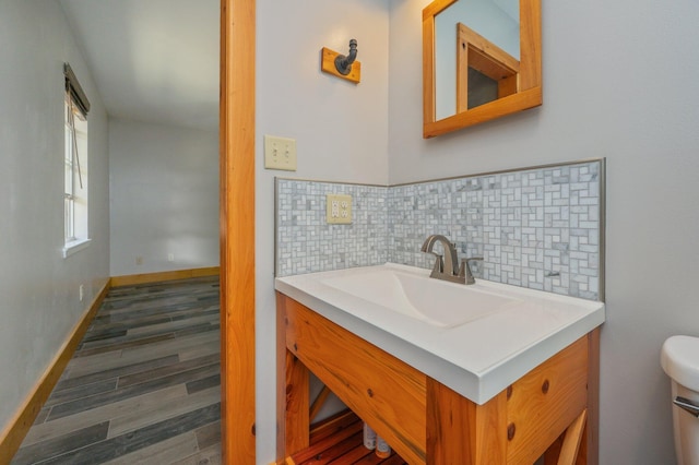 bathroom featuring vanity, backsplash, wood-type flooring, and toilet