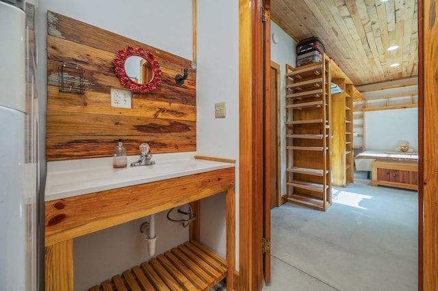 bathroom with sink, wooden ceiling, and wood walls