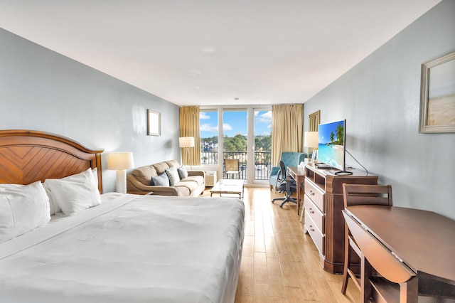 bedroom featuring access to outside, light hardwood / wood-style floors, and floor to ceiling windows