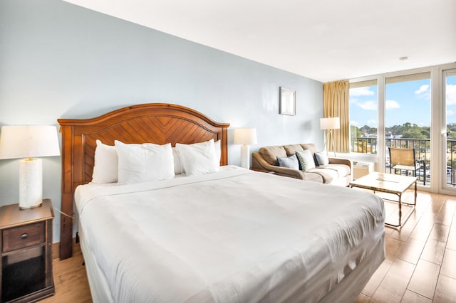 bedroom featuring expansive windows, light hardwood / wood-style flooring, and access to outside