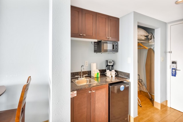 kitchen featuring fridge, sink, and light wood-type flooring