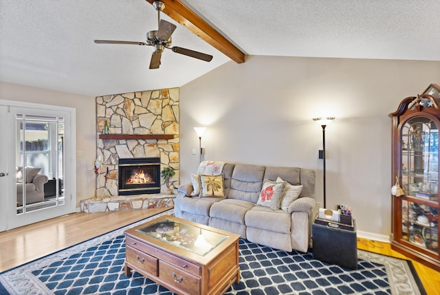 living room featuring hardwood / wood-style flooring, a stone fireplace, lofted ceiling with beams, and a textured ceiling