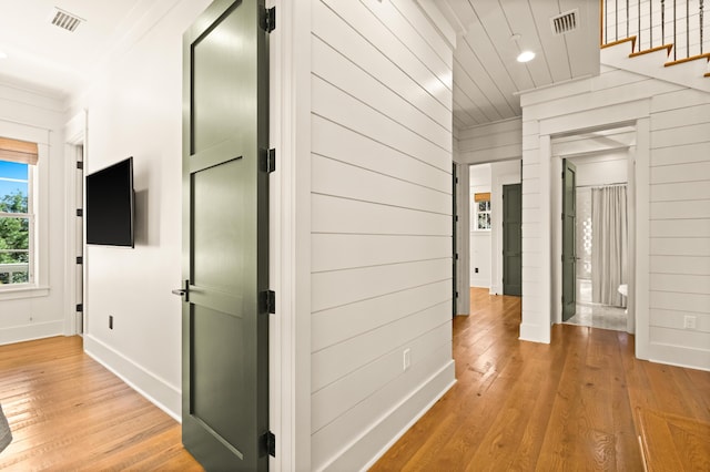 corridor with ornamental molding, wood-type flooring, and wood walls