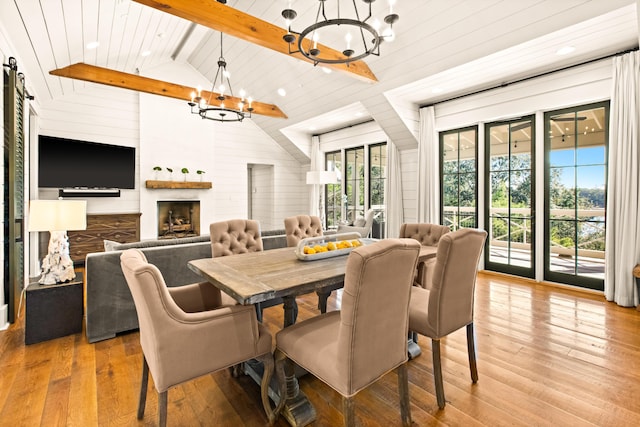 dining room with wood walls, an inviting chandelier, high vaulted ceiling, beamed ceiling, and hardwood / wood-style floors