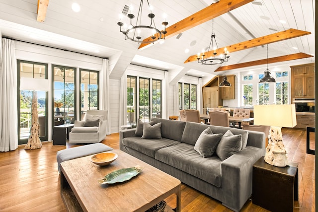 living room with vaulted ceiling with beams, a wealth of natural light, a notable chandelier, and light hardwood / wood-style flooring