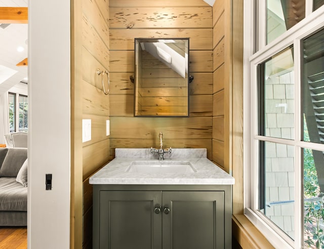 bathroom with vanity, a healthy amount of sunlight, and wood walls