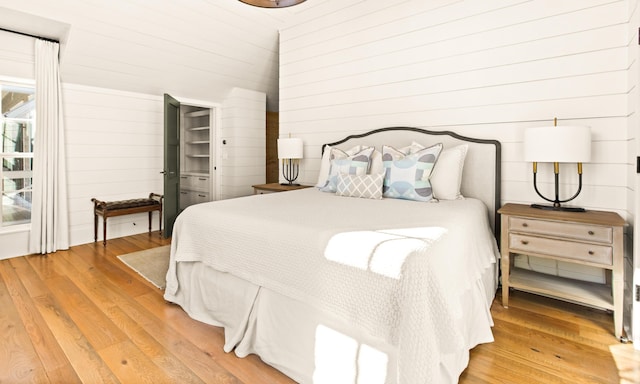 bedroom with hardwood / wood-style floors and wooden walls