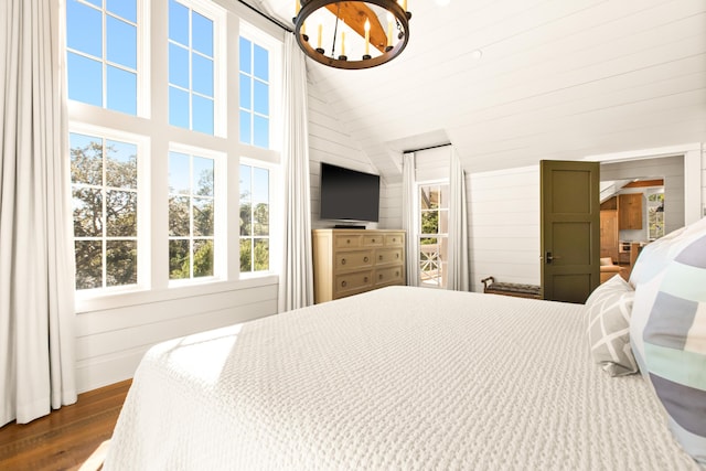 bedroom featuring dark hardwood / wood-style flooring, a notable chandelier, vaulted ceiling, and wooden walls