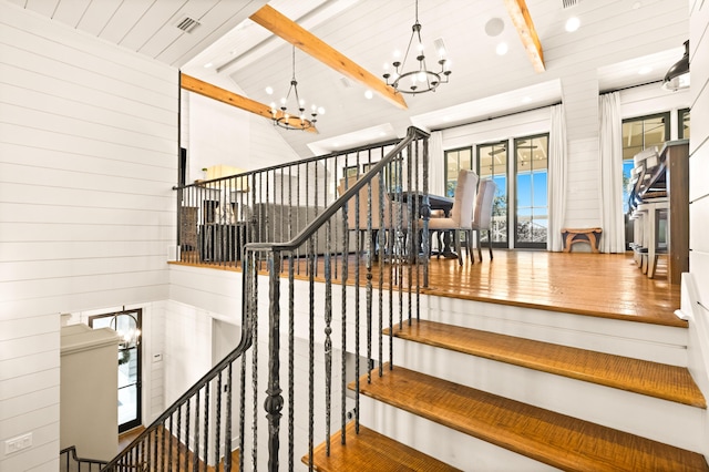 staircase featuring lofted ceiling with beams, wooden walls, wood ceiling, and a chandelier