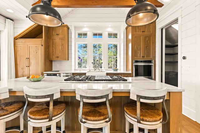 kitchen with lofted ceiling, appliances with stainless steel finishes, a kitchen breakfast bar, and wood walls