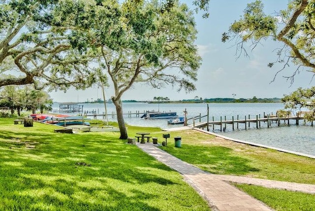 view of dock with a yard and a water view