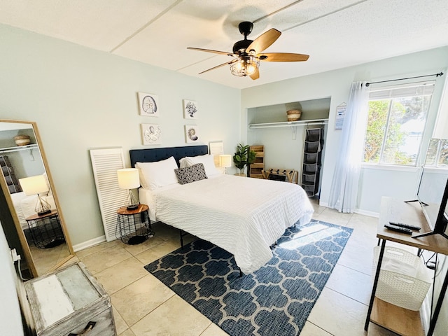 bedroom with light tile patterned flooring, a textured ceiling, ceiling fan, and a closet