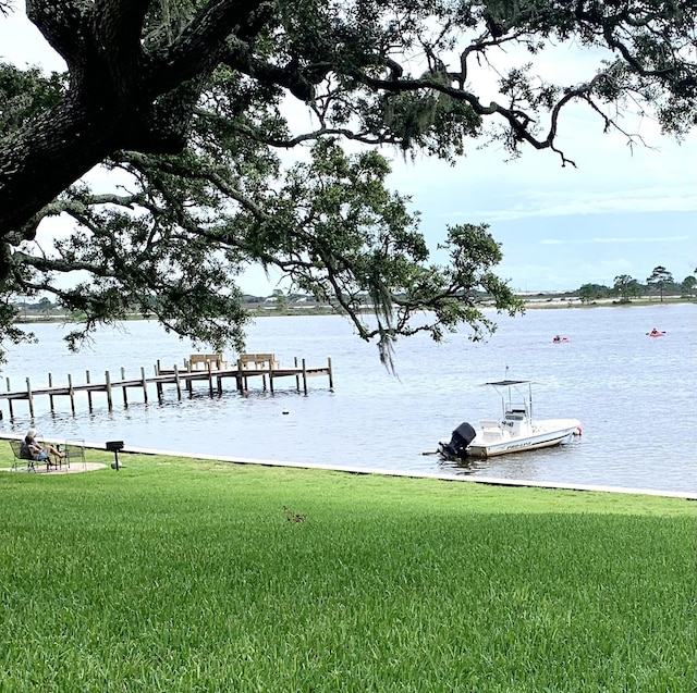 dock area with a lawn and a water view