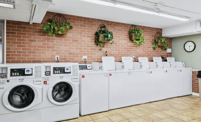 washroom with independent washer and dryer and brick wall