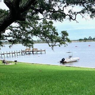 view of dock with a lawn and a water view