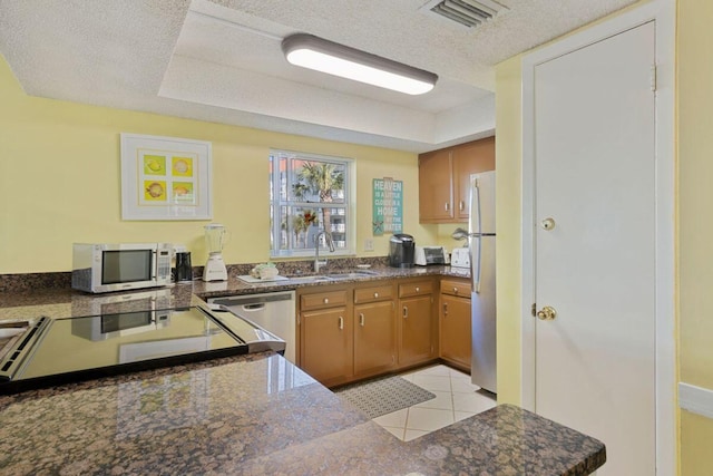 kitchen with sink, a textured ceiling, appliances with stainless steel finishes, kitchen peninsula, and a raised ceiling