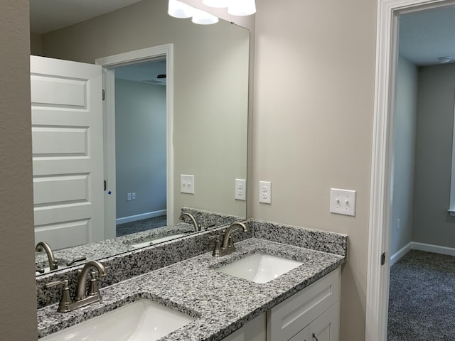 bathroom with double vanity, baseboards, and a sink