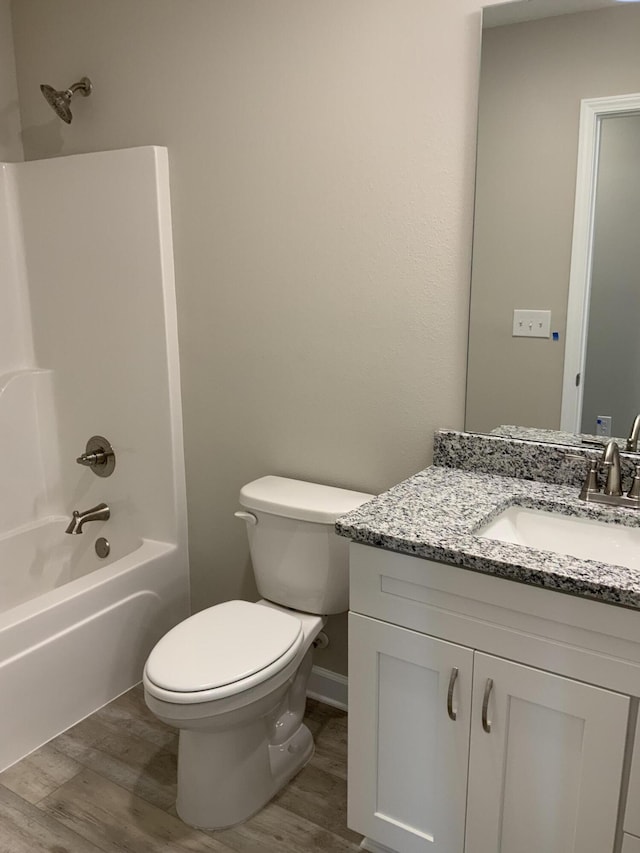 bathroom featuring toilet, shower / bathing tub combination, wood finished floors, and vanity