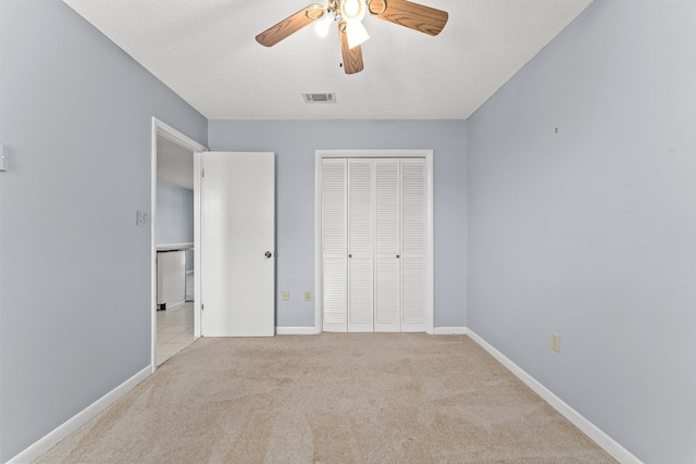 unfurnished bedroom featuring light carpet, a closet, and ceiling fan