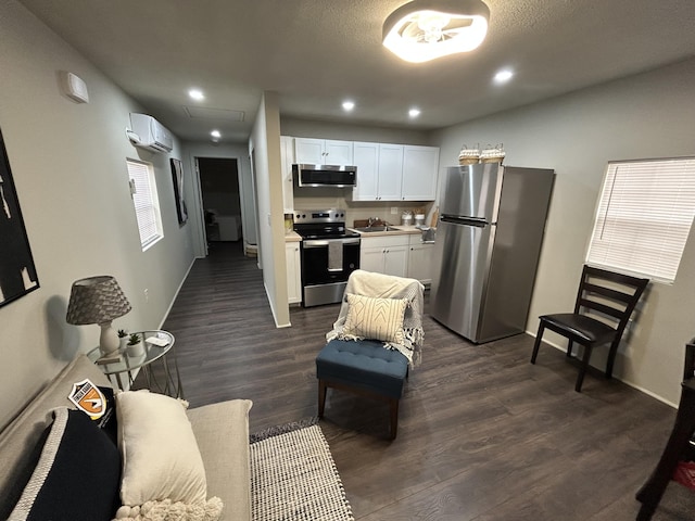 kitchen featuring sink, a wall mounted air conditioner, dark hardwood / wood-style flooring, stainless steel appliances, and white cabinets