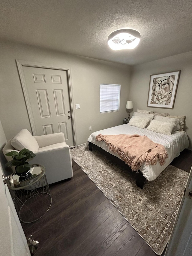 bedroom with dark hardwood / wood-style floors and a textured ceiling