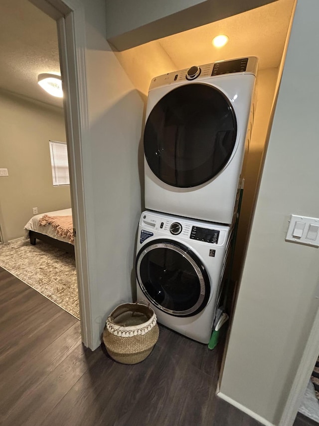 laundry room featuring stacked washer and dryer, dark hardwood / wood-style floors, and a textured ceiling