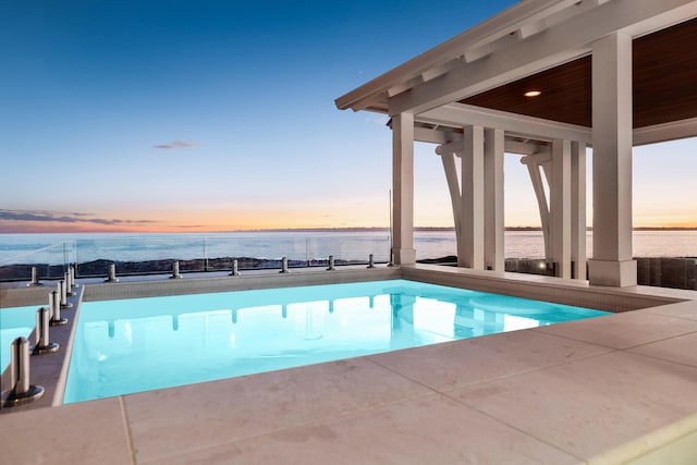 view of swimming pool with a patio area and a water view