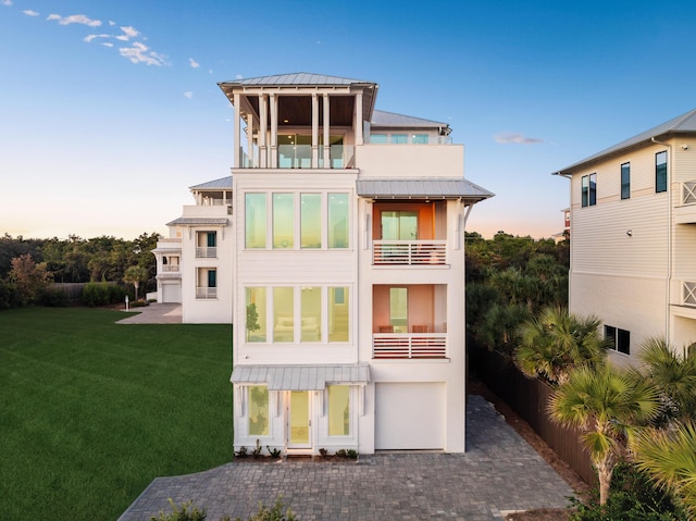 back of property featuring metal roof, a balcony, a lawn, stucco siding, and a standing seam roof