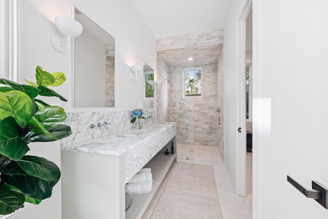 bathroom with double vanity, tile patterned flooring, a sink, and tiled shower