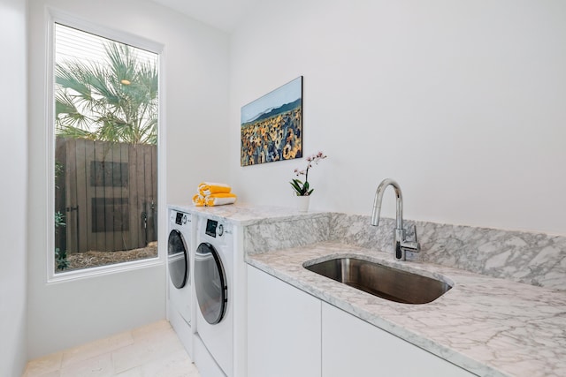 laundry room featuring washing machine and dryer, a sink, and cabinet space